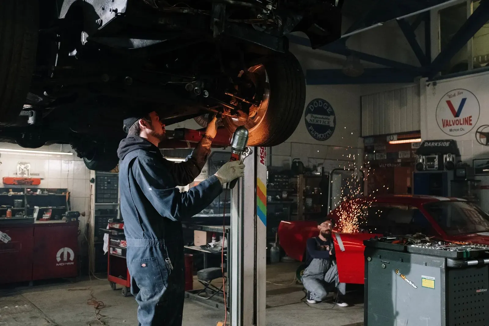 Sparks flying as a mechanic works under a car on a lift